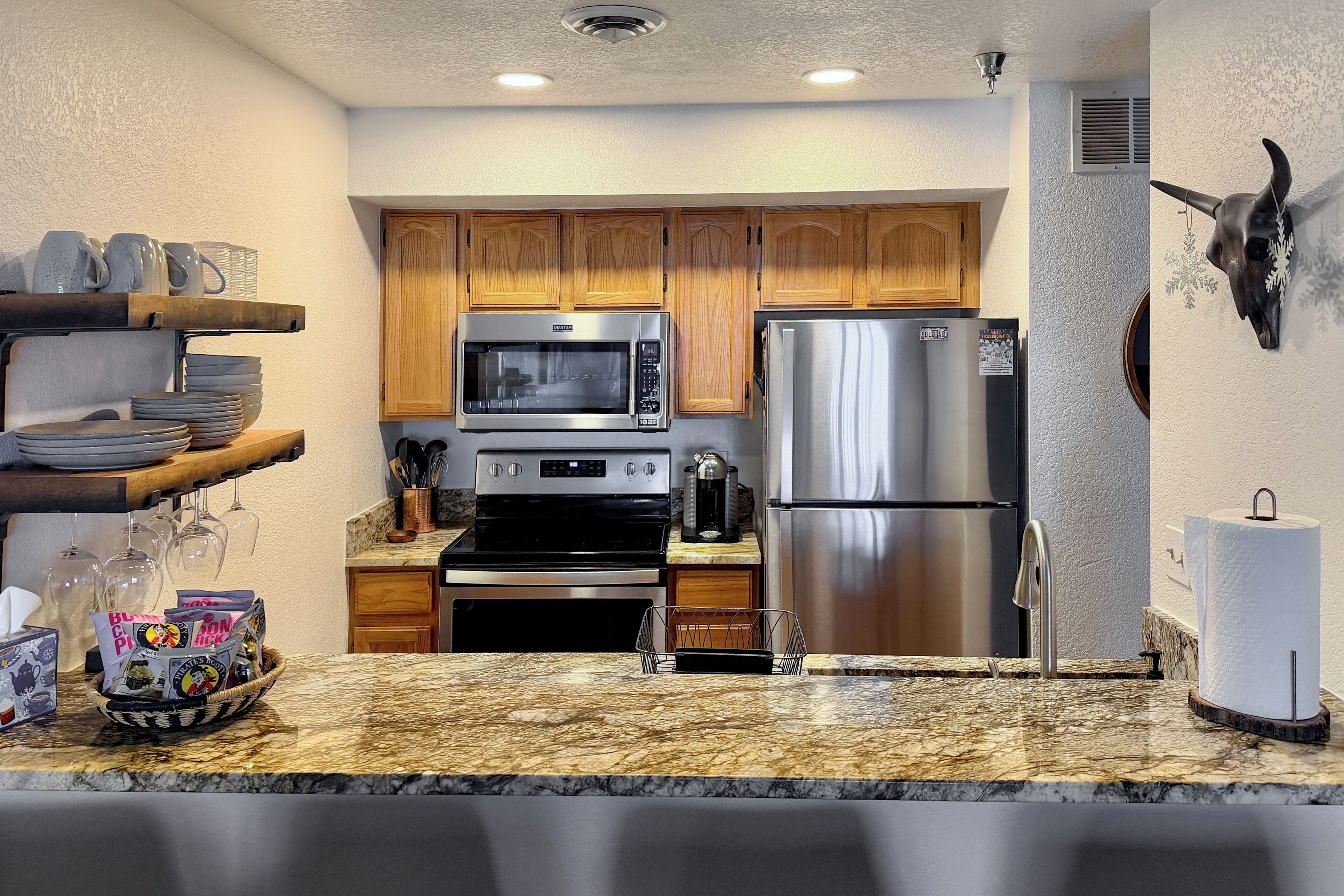A modern kitchen with wooden cabinets, stainless steel appliances, and a marble countertop.
