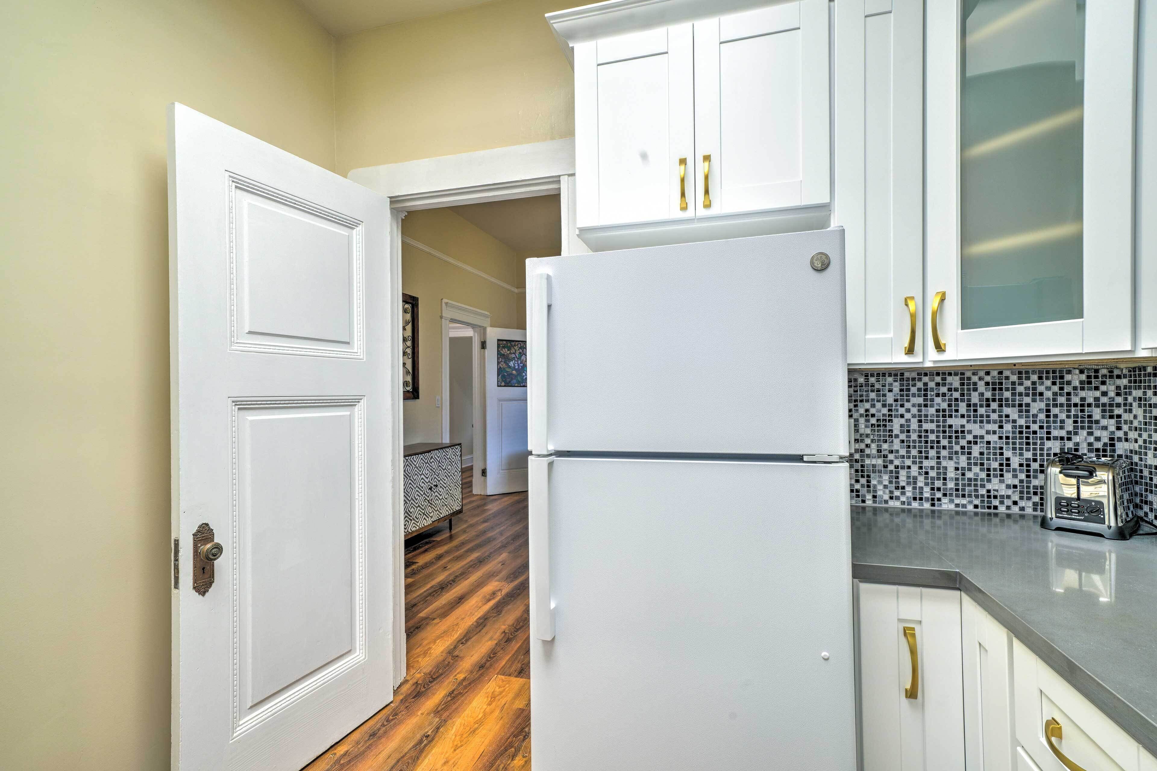 A kitchen with white cabinets, a refrigerator, and a toaster.