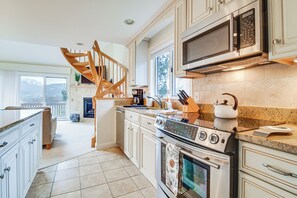 Une cuisine avec un escalier en bois, des appareils électroménagers en acier inoxydable et une grande fenêtre.