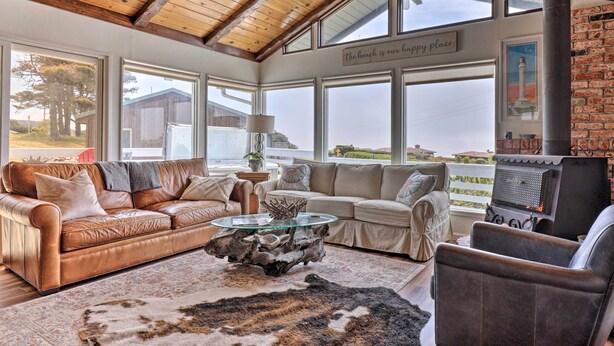 A cozy living room with a leather sofa, a glass coffee table, and a rustic fireplace. - Irish Beach Cottage w/ Beach Access & Ocean Views (Manchester)