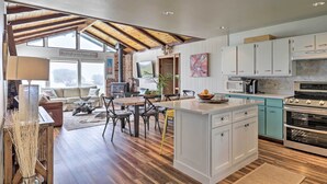 A spacious kitchen with white cabinets, a central island, and a dining area with a sofa and chairs. - Irish Beach Cottage w/ Beach Access & Ocean Views (Manchester)