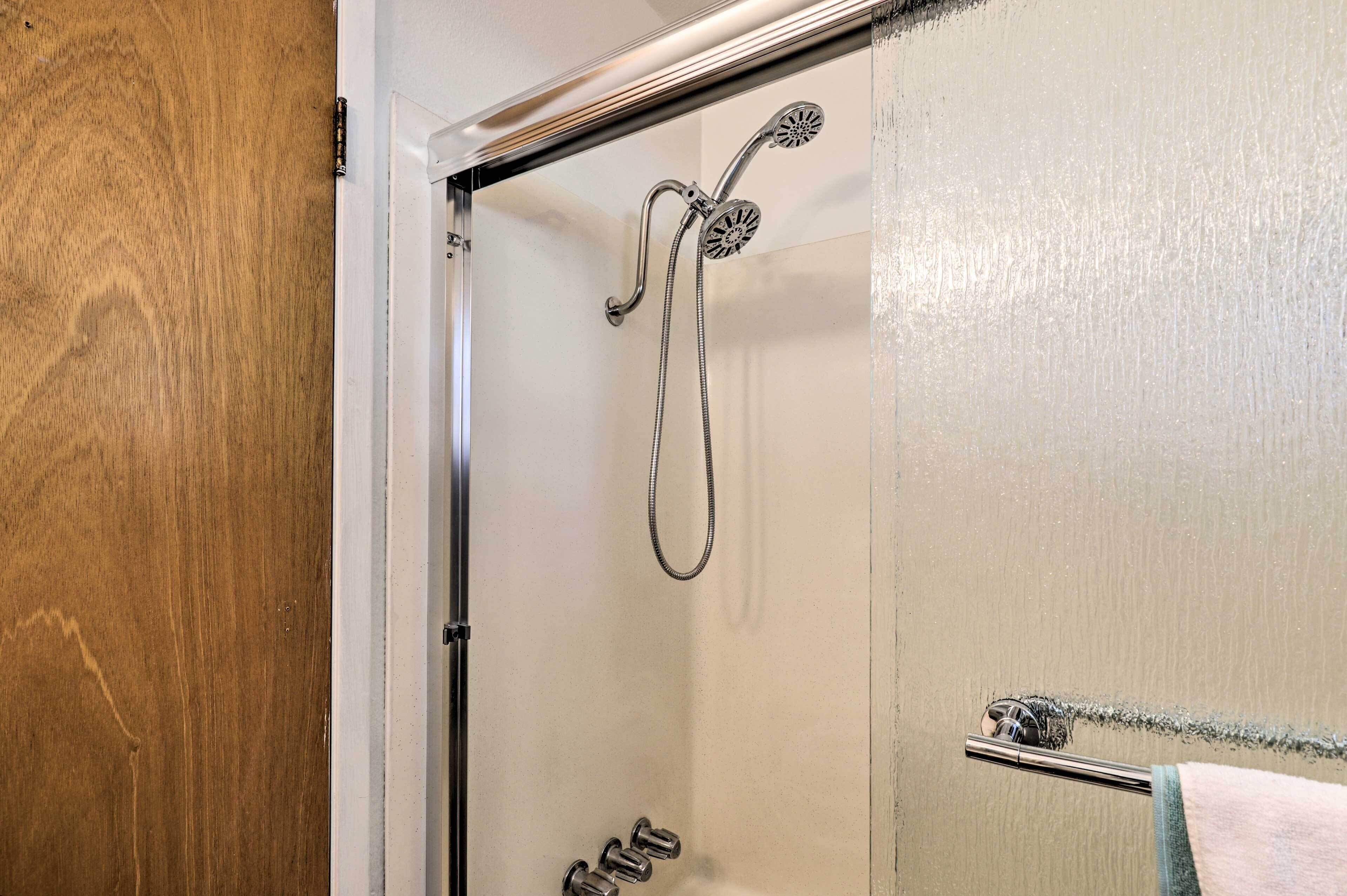 A shower with a handheld showerhead and a handheld shower attachment.