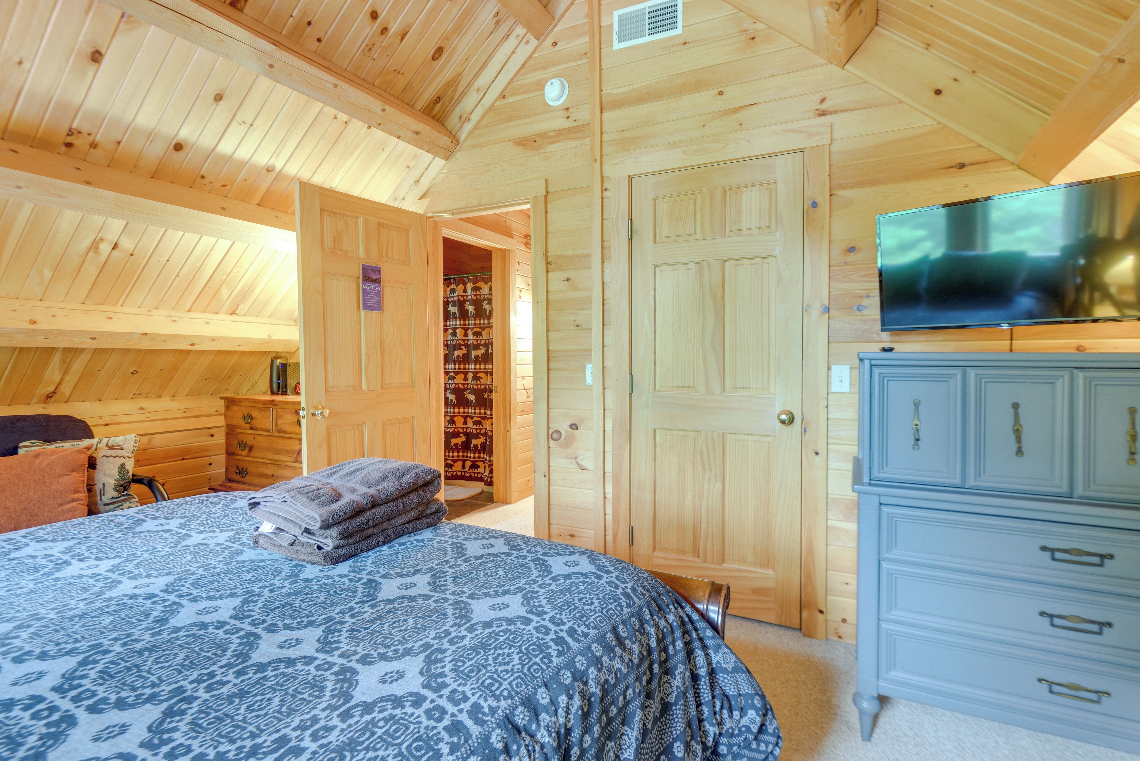 A wooden cabin bedroom with a bed, a television, and a wardrobe.