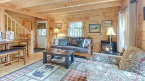 A cozy cabin interior with a wooden interior, a sofa, a coffee table, and a fireplace. - Updated Log Cabin Near Story Land & Diana's Baths! (Conway)