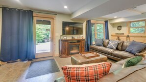 A living room with a leather sofa, a wooden cabinet, and a television. - Updated Log Cabin Near Story Land & Diana's Baths! (Conway)