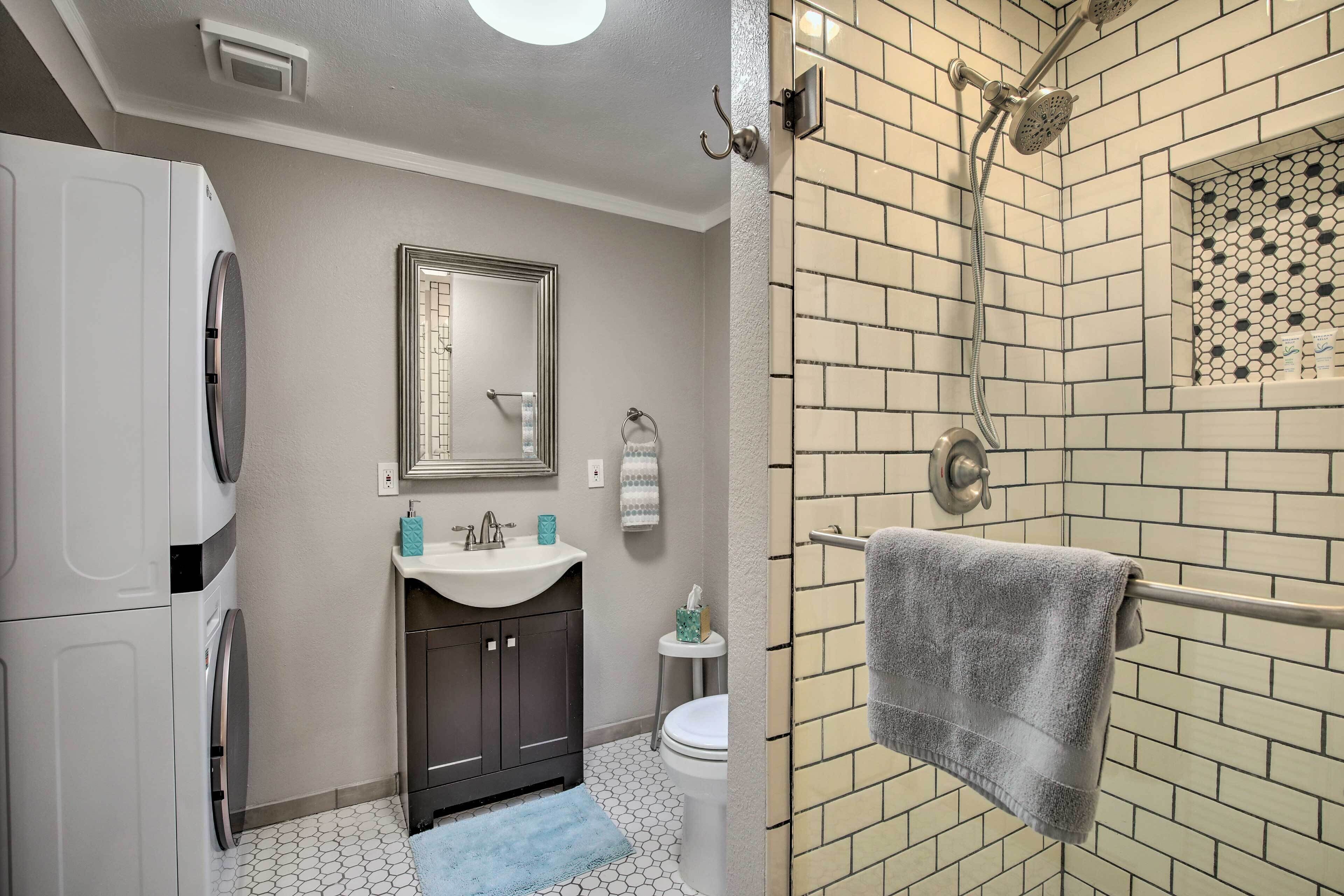 Une salle de bain avec un lavabo blanc, des meubles sombres, des toilettes et une douche équipée d’un porte-serviettes.