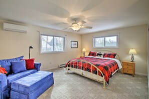 A bedroom with a bed, a blue sofa, a wooden nightstand, and a ceiling fan.