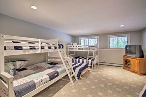 Een slaapkamer met stapelbed, televisie en kast.