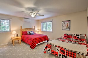 A bedroom with two beds, a ceiling fan, and a window with a view of trees.