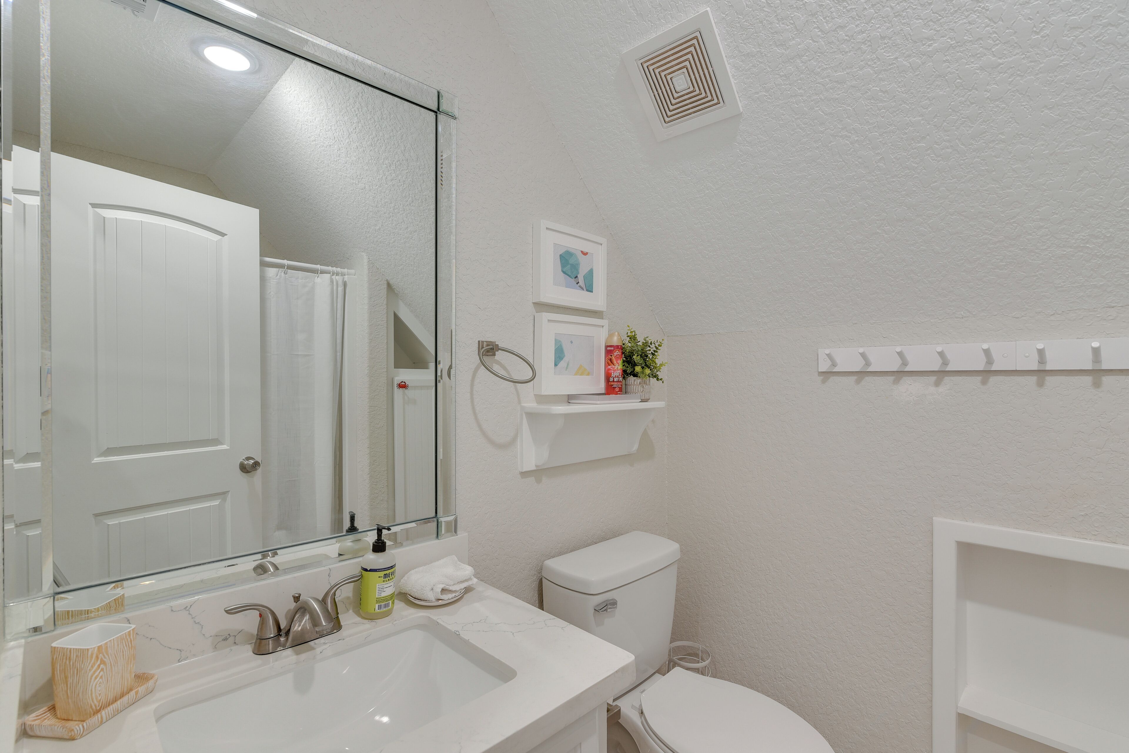 A bathroom with a white sink, mirror, toilet, and a towel rack.