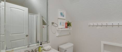 A bathroom with a white sink, mirror, toilet, and a towel rack.
