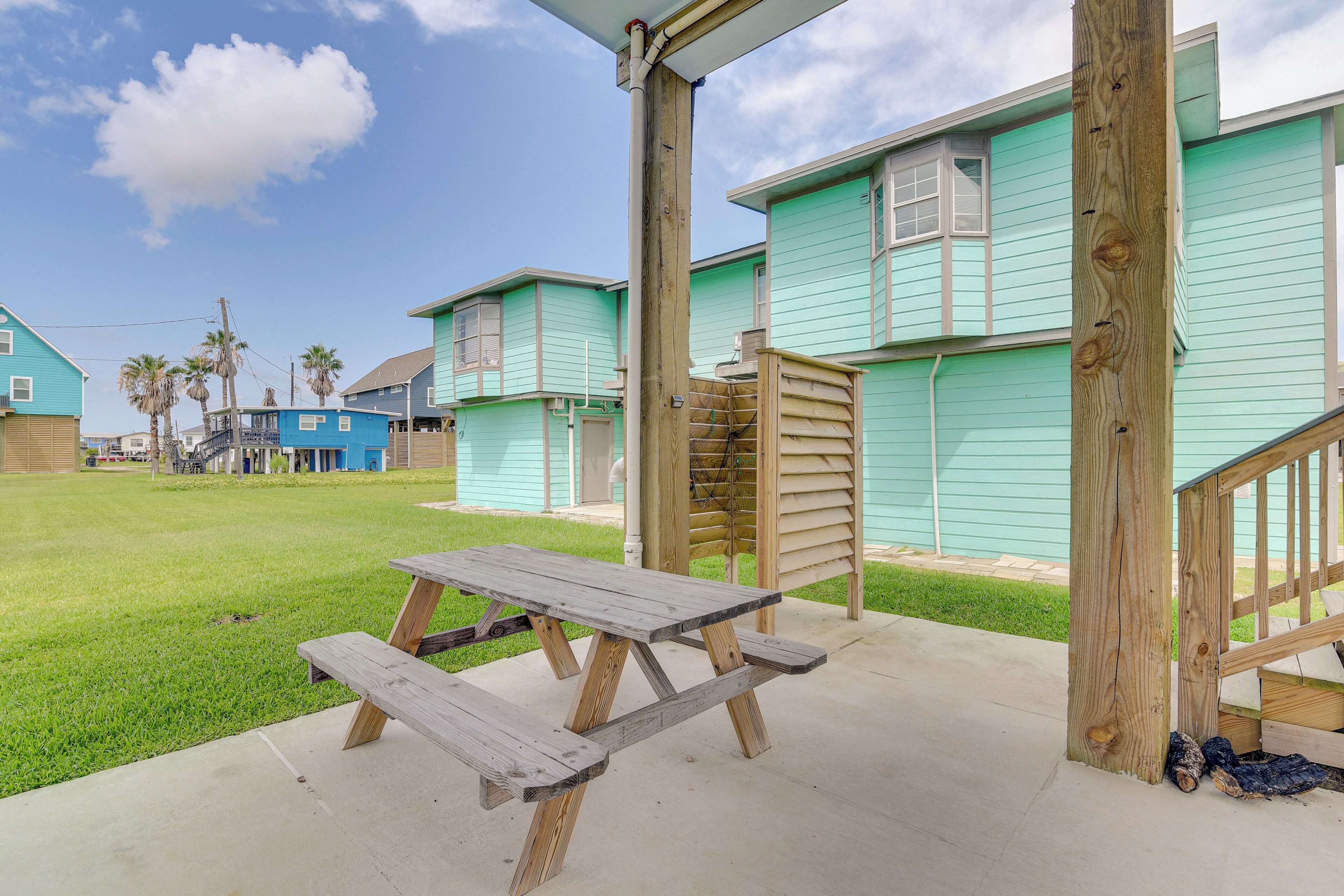 A picnic table on a concrete patio with a wooden fence and a wooden structure nearby.