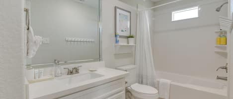 Een moderne badkamer met een wit wastafelmeubel, een toilet en een bad.