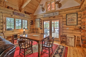 A rustic cabin interior with a wooden dining table, chairs, a red rug, and mounted animal heads on the walls. - Waterfront Conway Vacation Rental w/ Deck! (Center Conway)