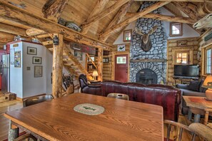 A rustic lodge interior with a stone fireplace, leather seating, and a wooden dining table. - Waterfront Conway Vacation Rental w/ Deck! (Center Conway)
