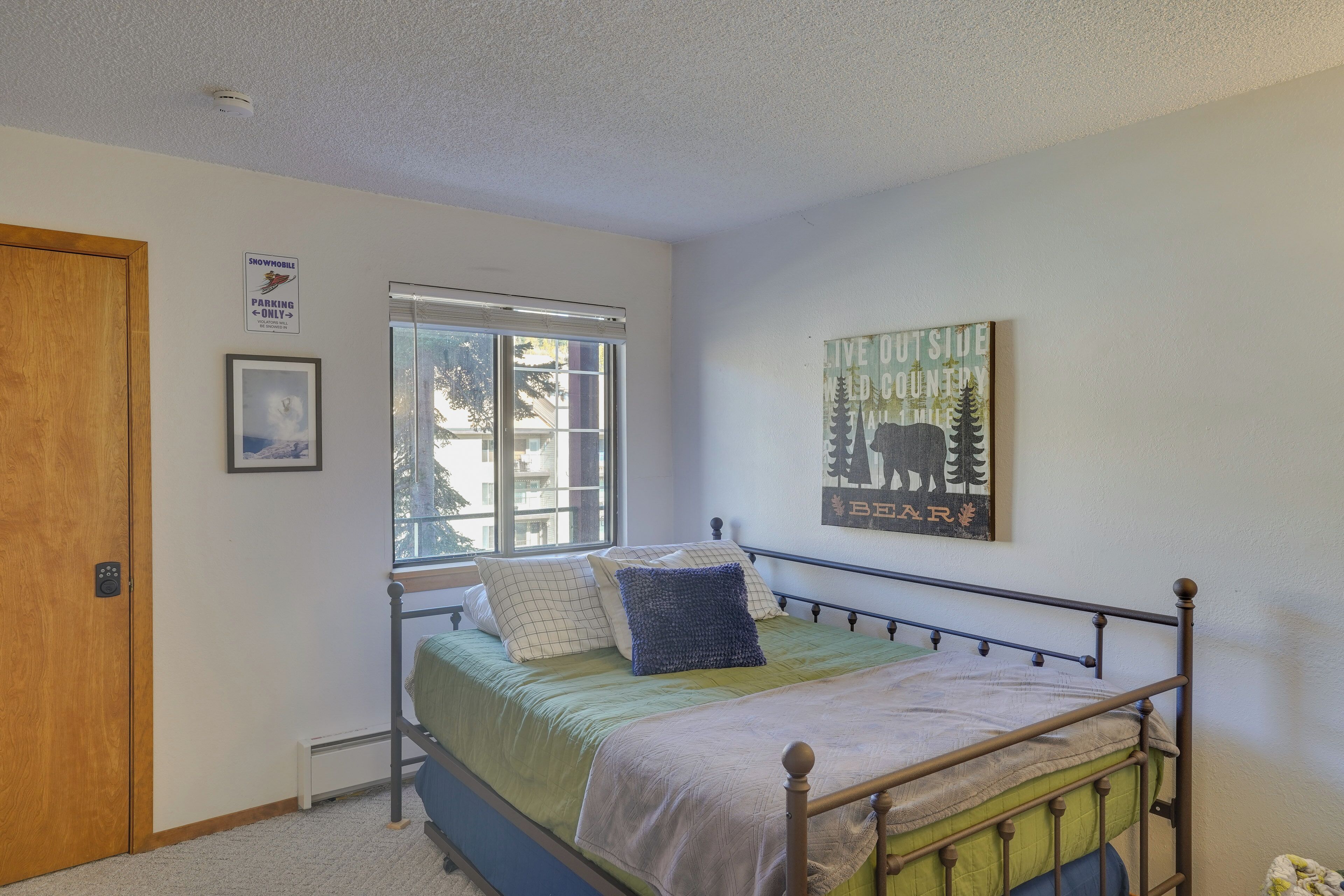 A bedroom with a bed, a window, a door, and a wall-mounted sign.