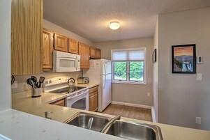 Una cocina con armarios de madera, microondas, estufa, tostadora y refrigerador.