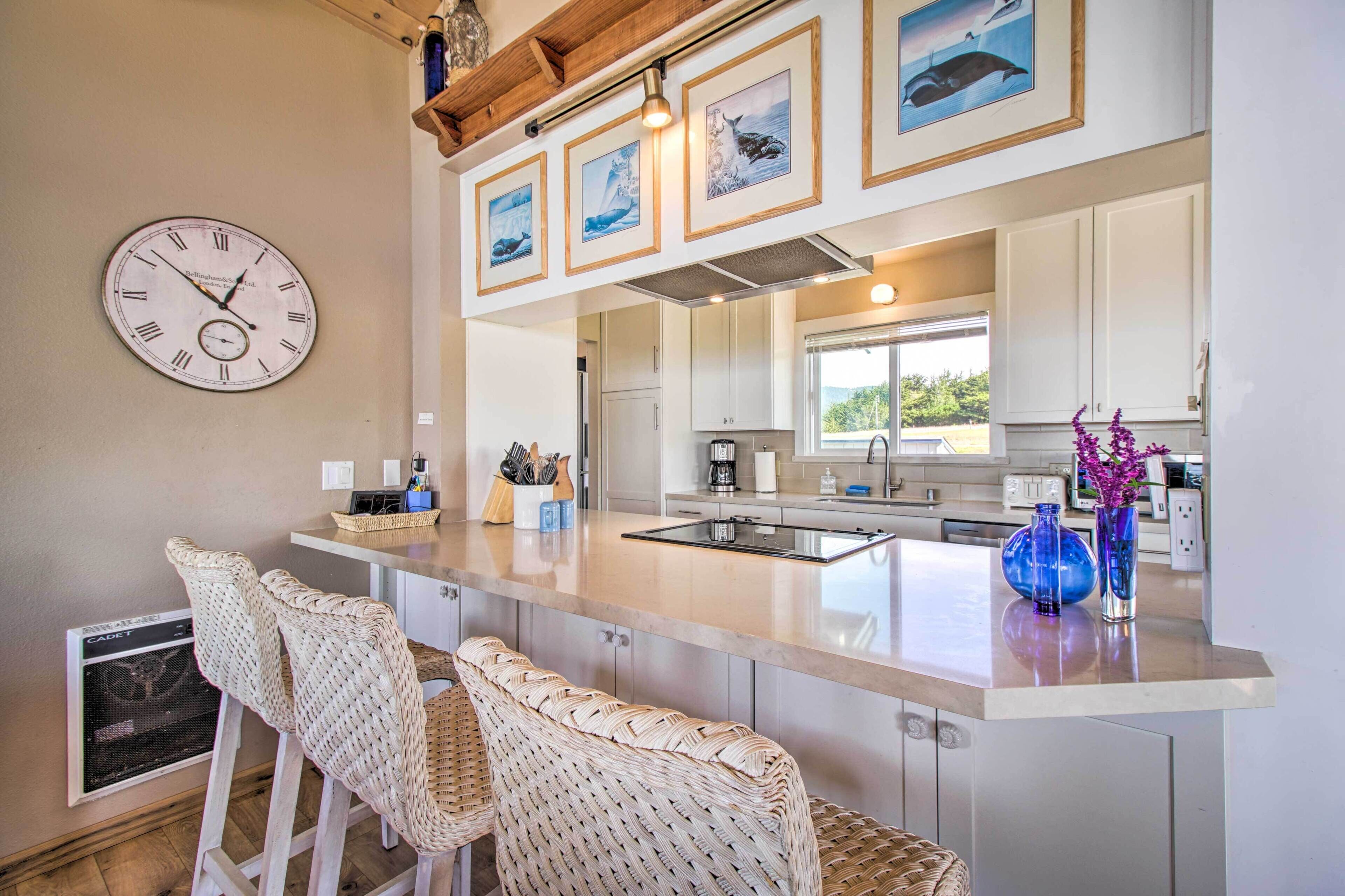 Una cucina moderna con isola centrale, sgabelli da bar, un orologio e opere d'arte incorniciate sopra l'isola.