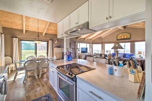 A spacious kitchen with a large island, wooden ceiling beams, and a view of the outdoors. - Spectacular Ocean View Retreat w/ Hot Tub (Manchester)
