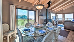 Un comedor con una mesa de vidrio dispuesta para seis personas, rodeado de sillas de mimbre y vistas al exterior.