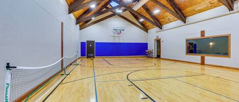 An indoor basketball court with a wooden ceiling and blue padded walls.
