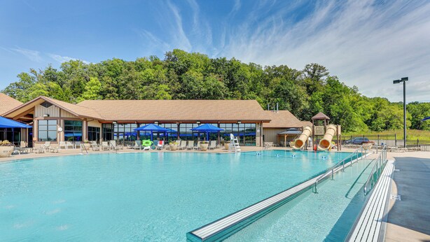 A large outdoor swimming pool with a covered seating area and a play structure.
