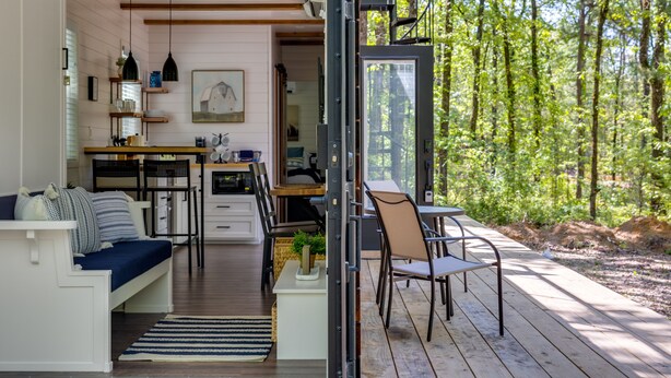 En modern inredning med ett kök, en matplats och ett stort fönster med utsikt över en skog.