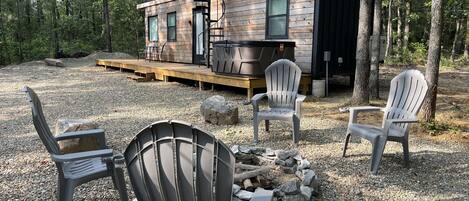 Une cabane dotée d’une terrasse, d’un espace salon extérieur et d’un foyer.
