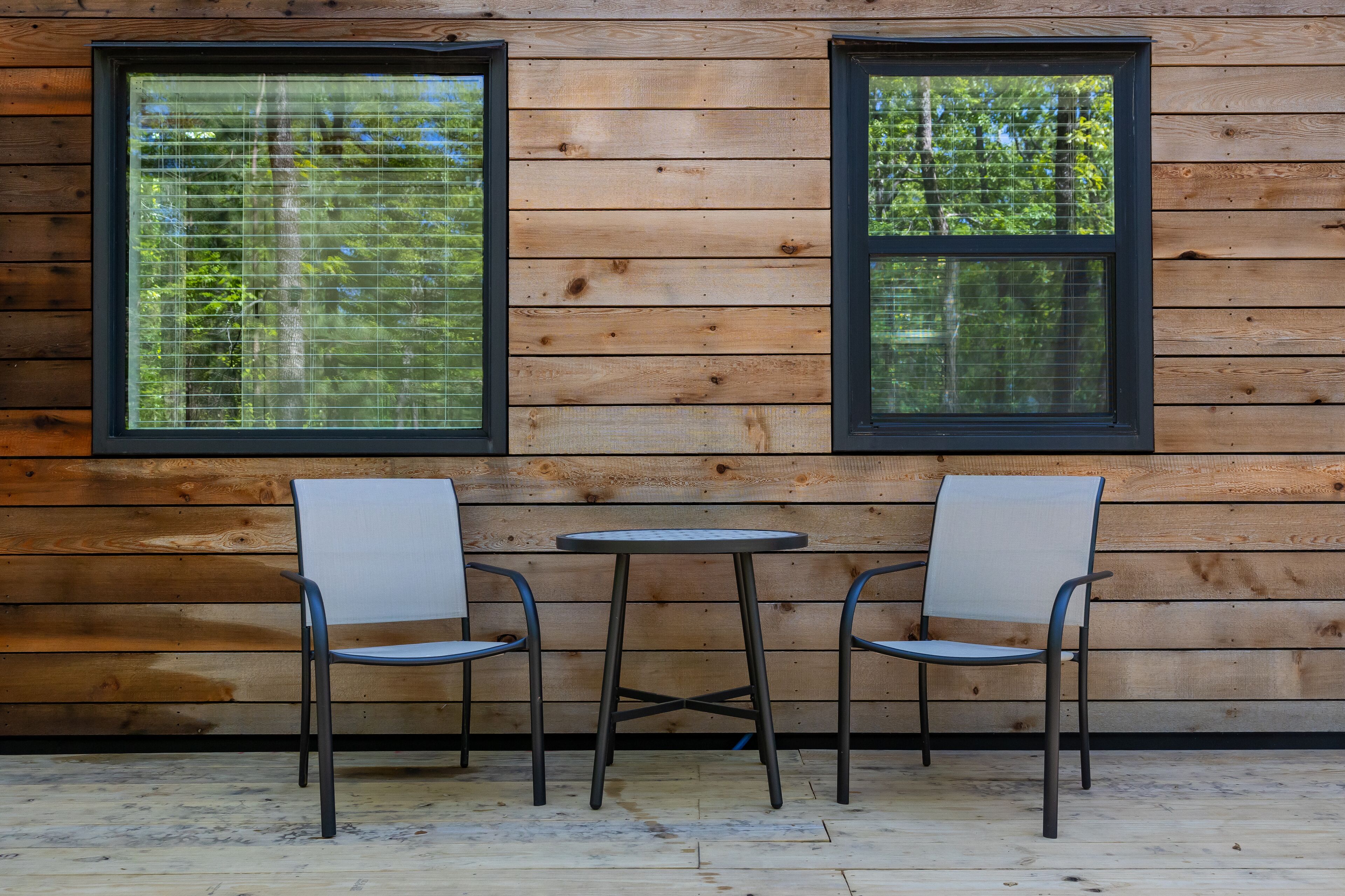 A wooden cabin with two windows and a small table with two chairs.