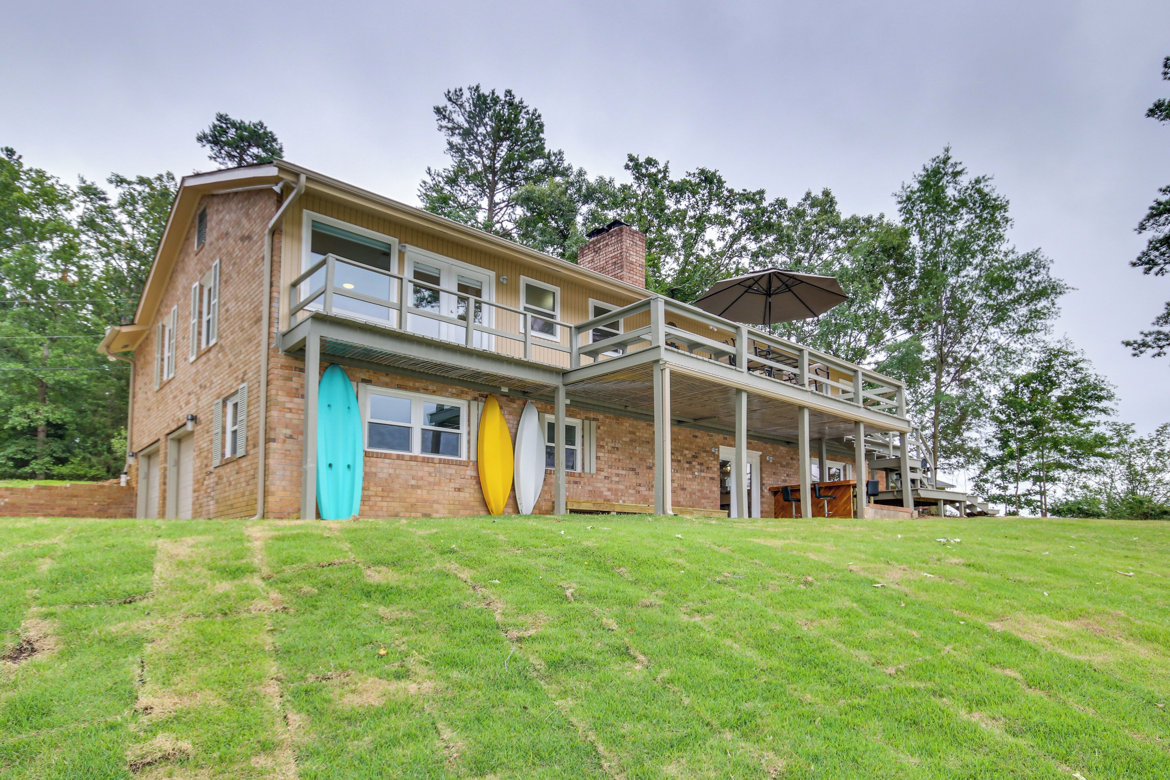 A two-story house with a covered patio, a brick exterior, and a grassy lawn.