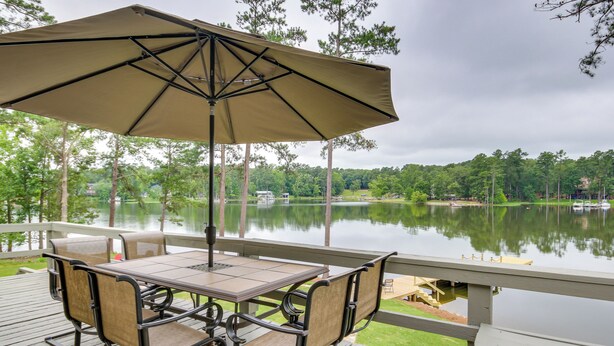 A deck with a table and chairs, overlooking a lake. - Waterfront Lakehouse w/ Private Dock & Fire Pit! (Chapin)