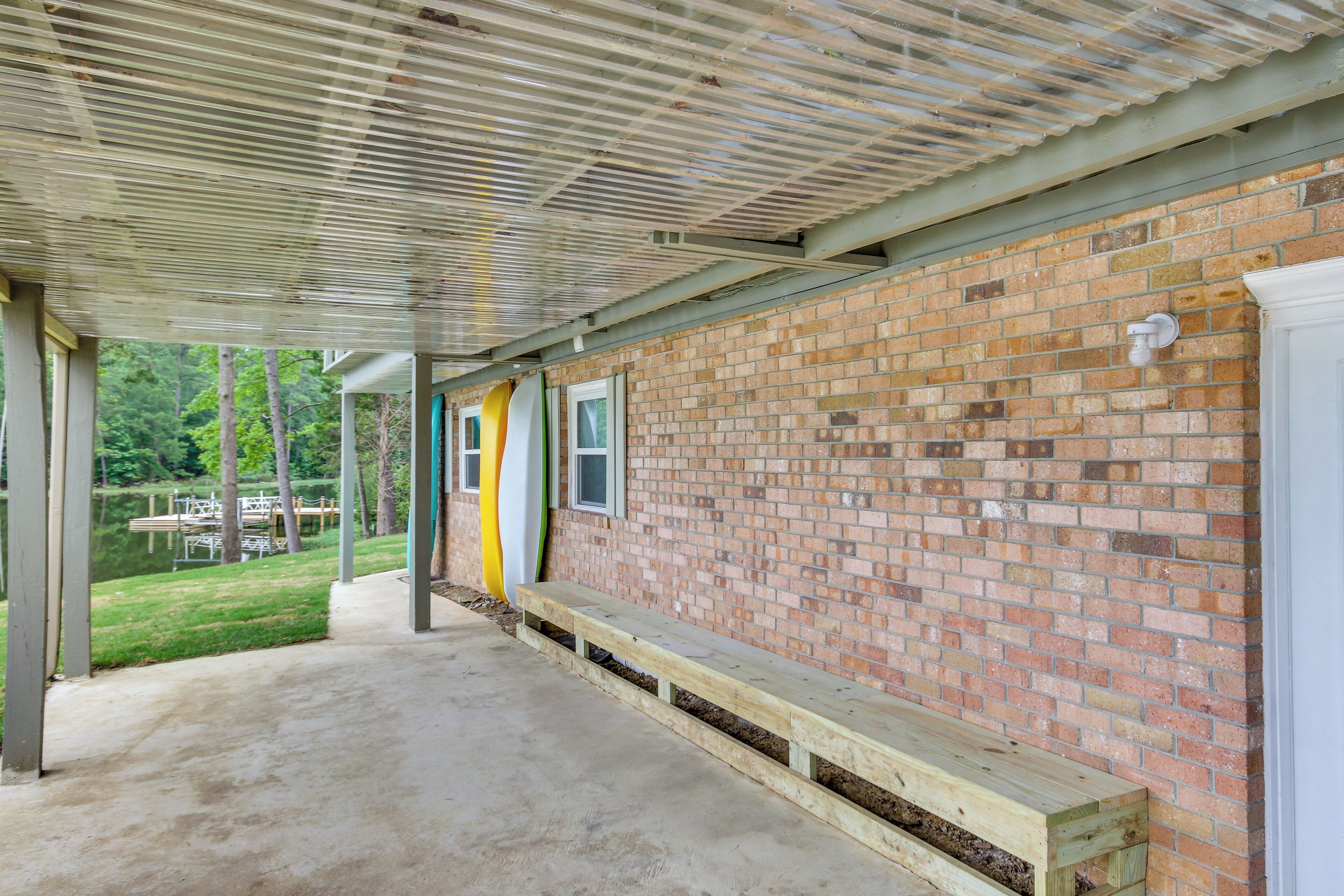 Un espace extérieur abrité, doté d’un mur en briques, de bancs en bois et d’un sol en béton.