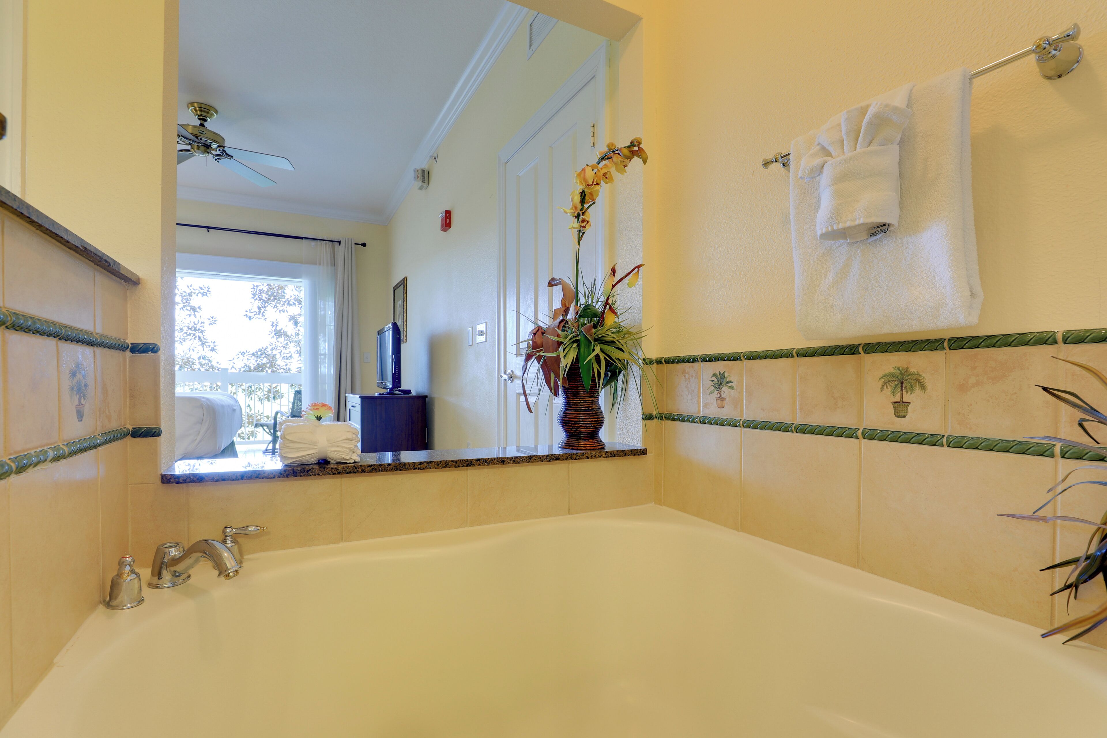 A bathroom with a bathtub, a mirror, a towel rack, and a potted plant.