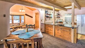 Un interior de madera con comedor, cocina y un gran ventanal.