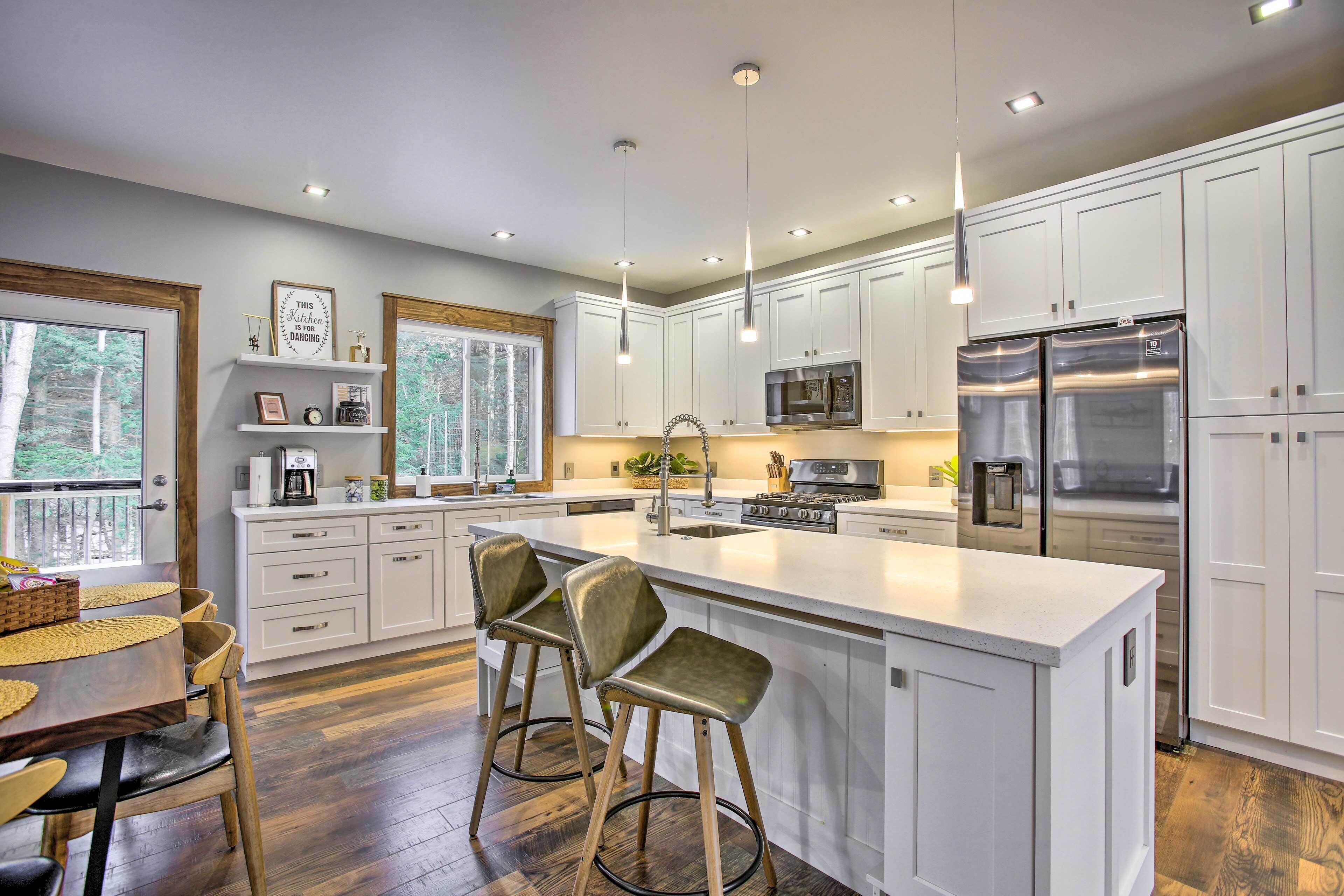 A modern kitchen with white cabinetry, stainless steel appliances, and a bar area with stools.
