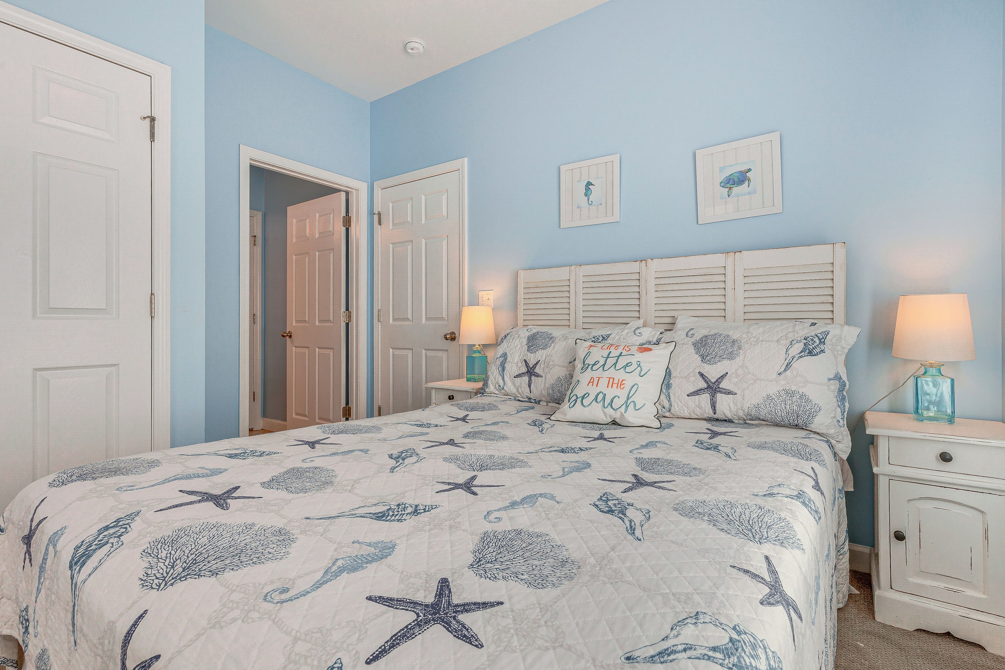 A bedroom with a bed, nightstands, and a door.