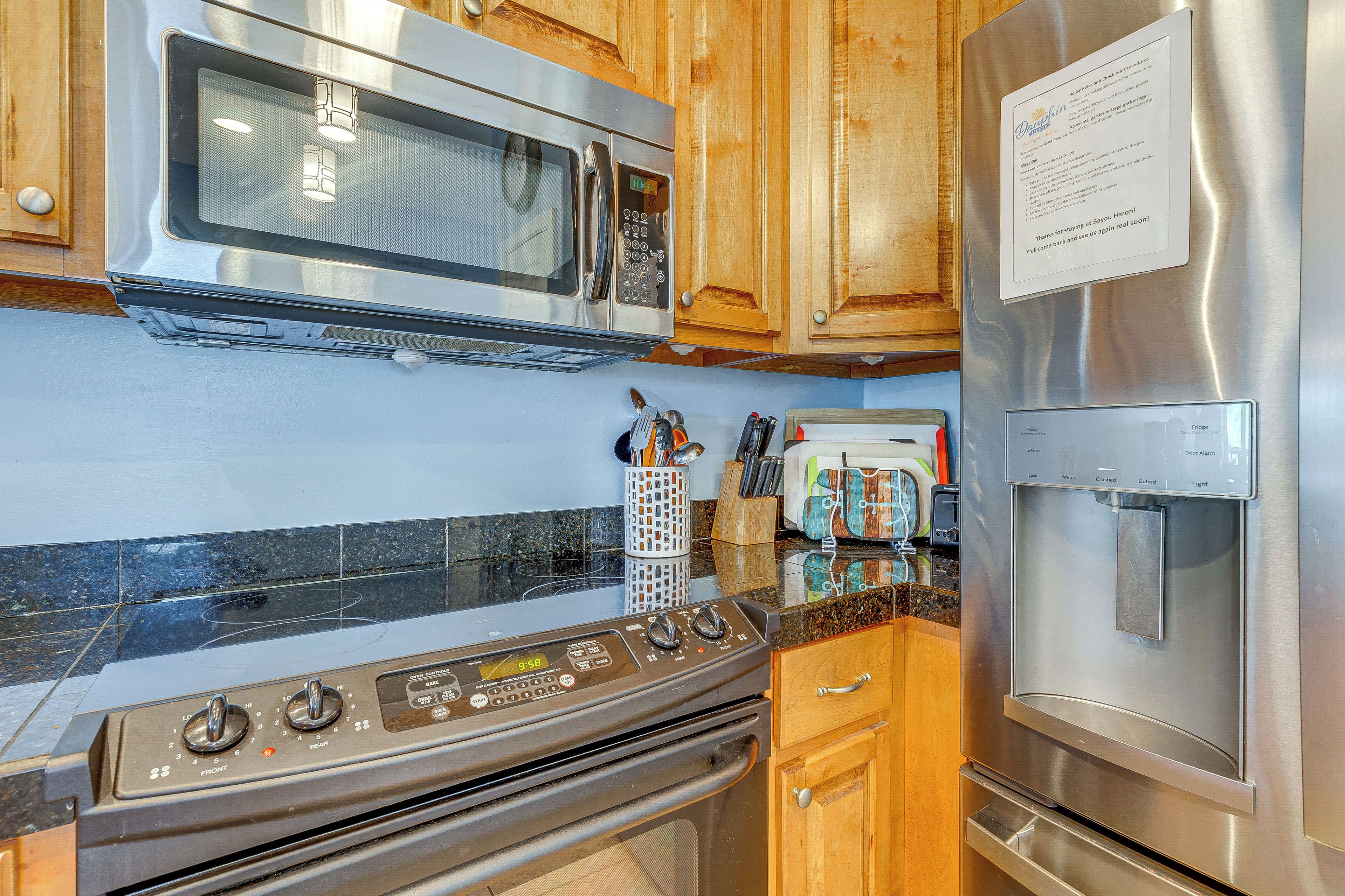 A kitchen with stainless steel appliances, wooden cabinets, and a granite countertop.