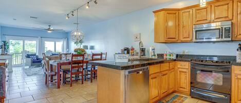 A spacious kitchen with wooden cabinets, stainless steel appliances, and a dining area with a chandelier.