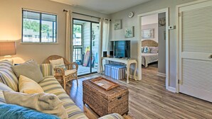 A cozy living room with a striped sofa, wicker ottoman, and a television. - Family-friendly Condo w/ Pools + Tennis Courts! (Hilton Head Island)