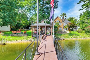 A wooden bridge over a pond leading to a gazebo with outdoor seating. - Luxe Lakefront Apartment w/ Shared Pool & Dock! (Chapin)