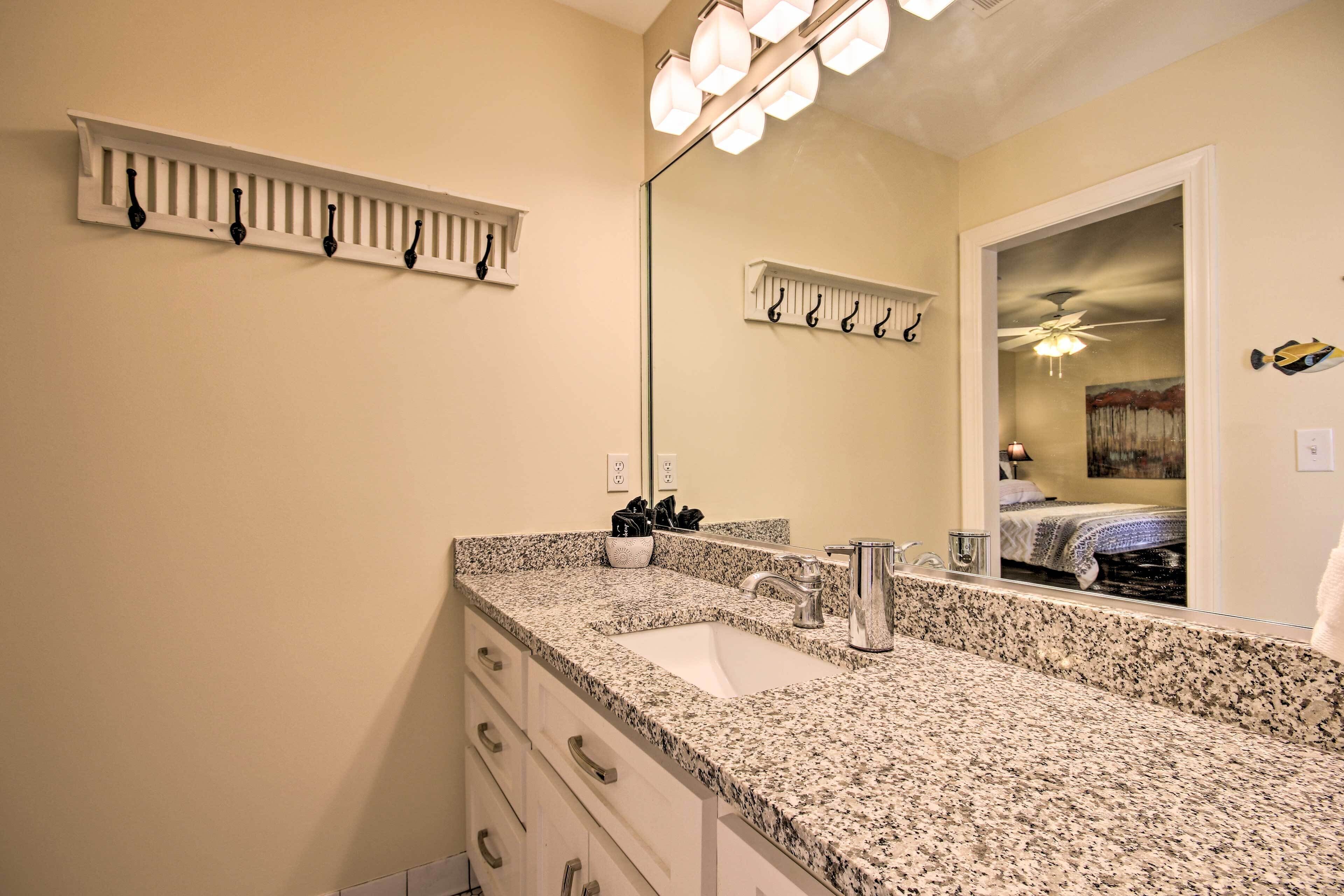 A bathroom with a granite countertop sink, a mirror, and a ceiling fan.