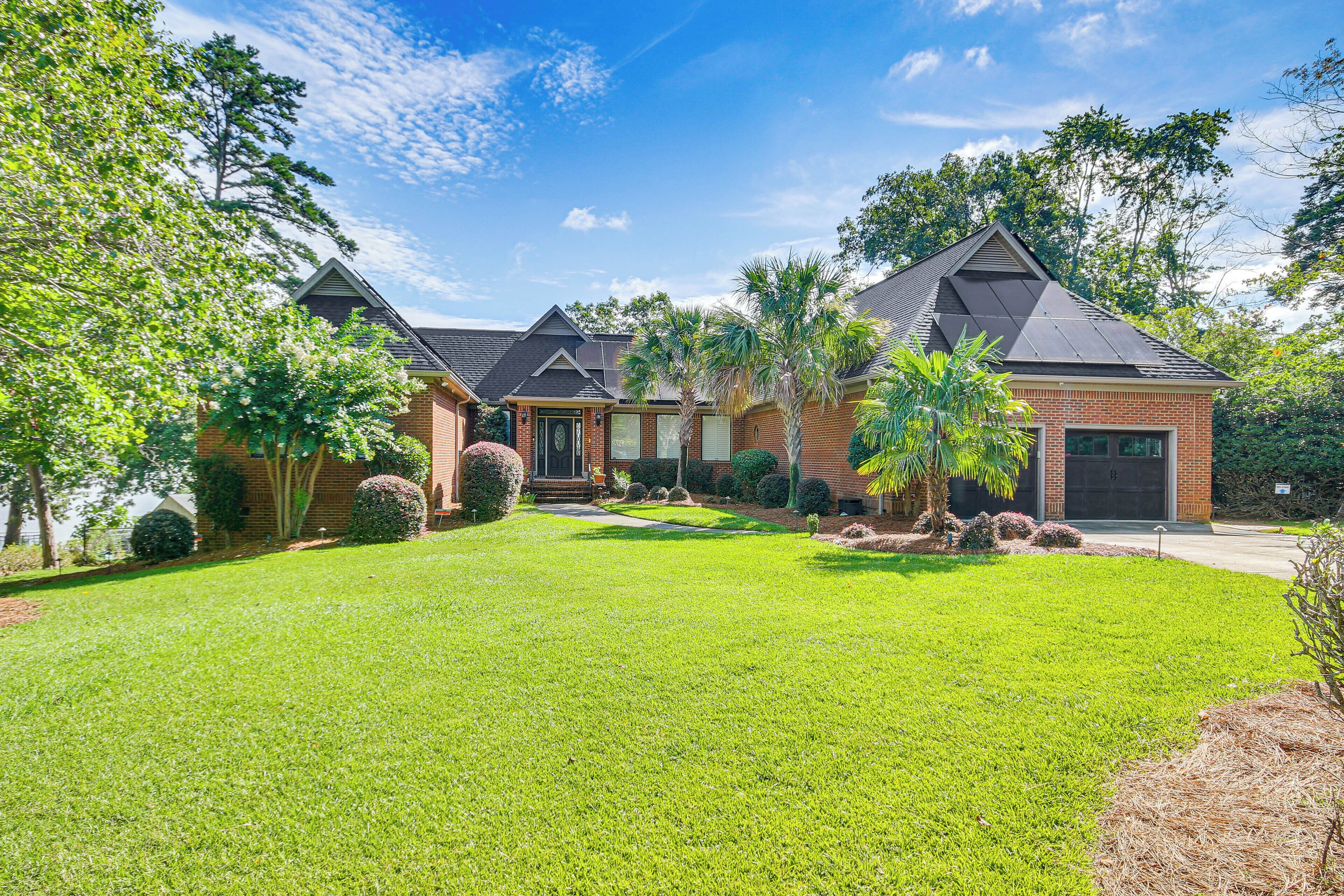 A residential property with a well-maintained lawn, multiple brick houses, and a variety of trees and shrubs.