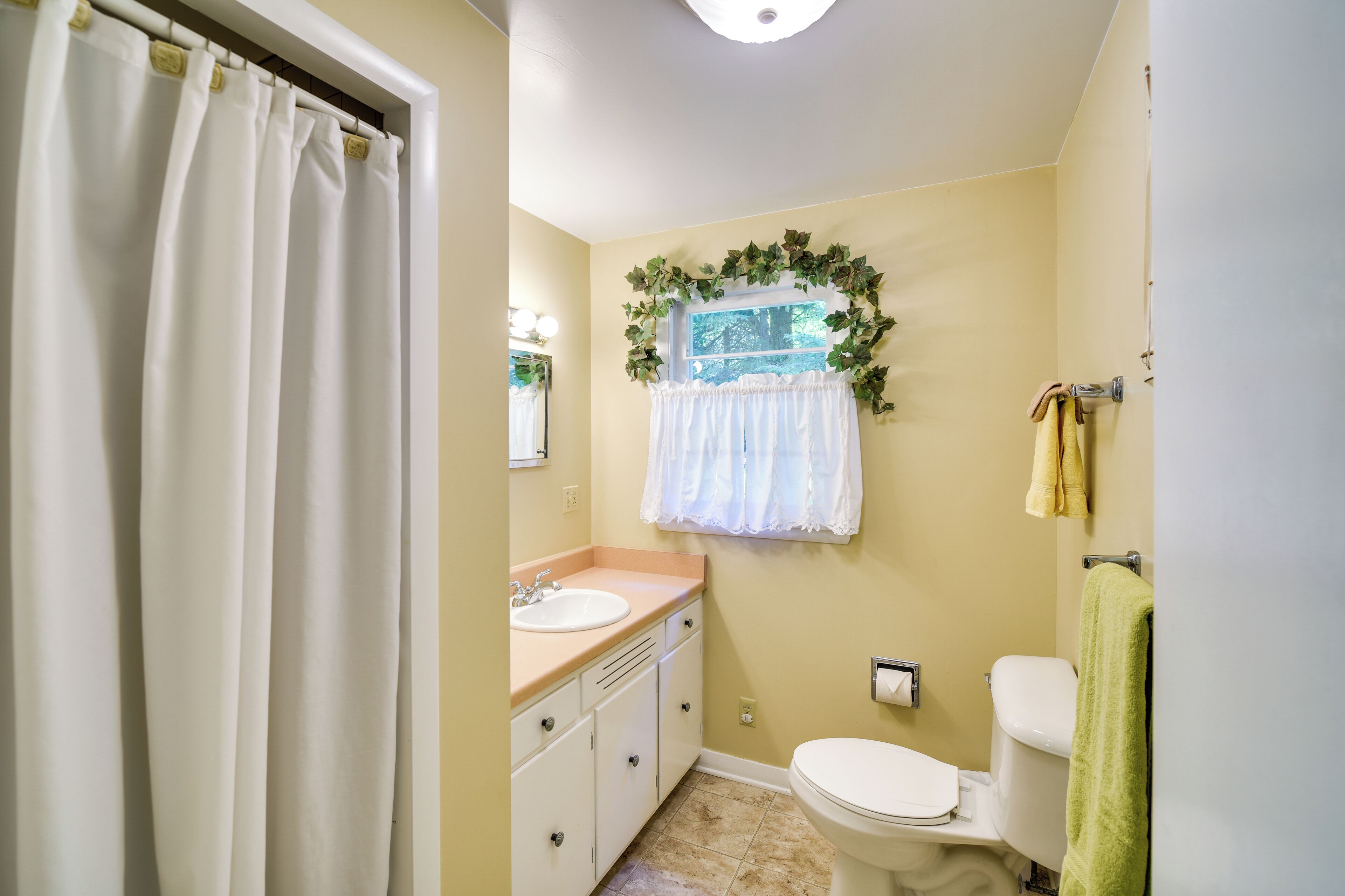 A bathroom with a toilet, sink, and shower curtain.