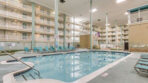 A multi-level hotel with a swimming pool, lounge chairs, and balconies.