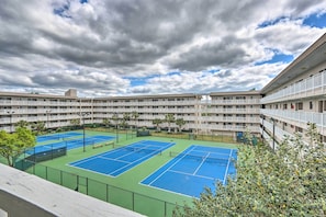 Un hotel de varios pisos con un complejo de canchas de tenis.