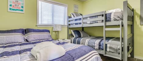 Een kamer met stapelbedden, een raam met zonwering, en een muur met een poster.