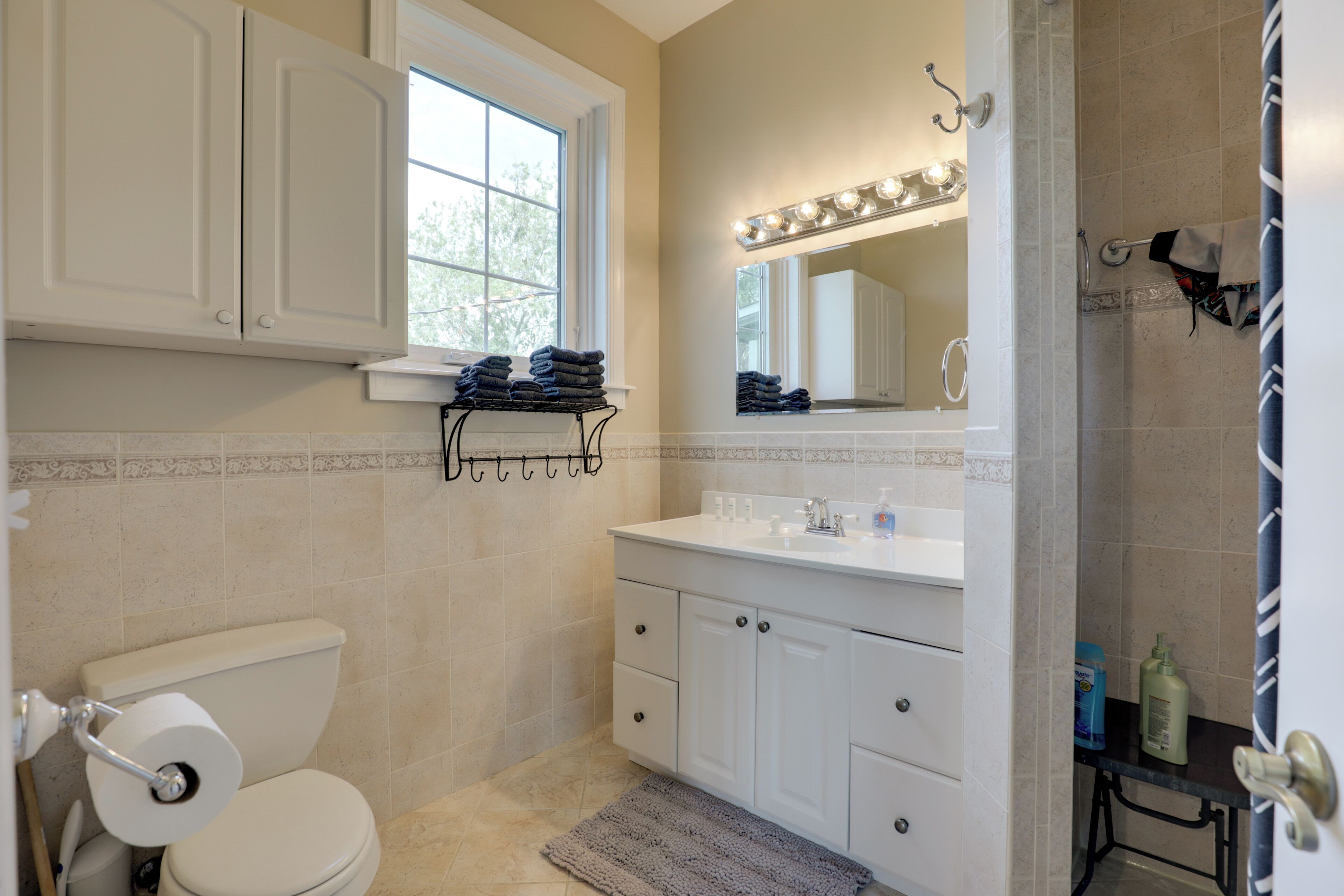 A bathroom with a toilet, sink, vanity, and a window.