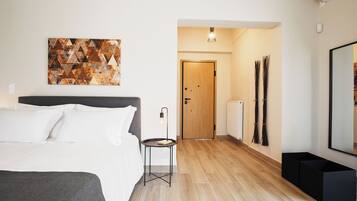 Habitación de hotel moderna con cama, una mesita, puerta de madera y una obra de arte colgada en la pared.