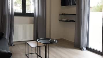 Una sala de estar moderna con un sofá, una mesita con un objeto decorativo, un televisor montado y estanterías empotradas.
