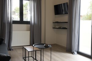 Una sala de estar moderna con un sofá, una mesita con un objeto decorativo, un televisor montado y estanterías empotradas.